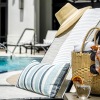 a hat and pillow on a sunbathing bed next to a pool